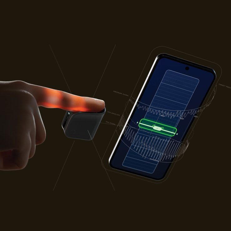 A finger rests on a small dark Biozen device, lit from within, beside a phone whose app traces pressure and PPG waveforms.